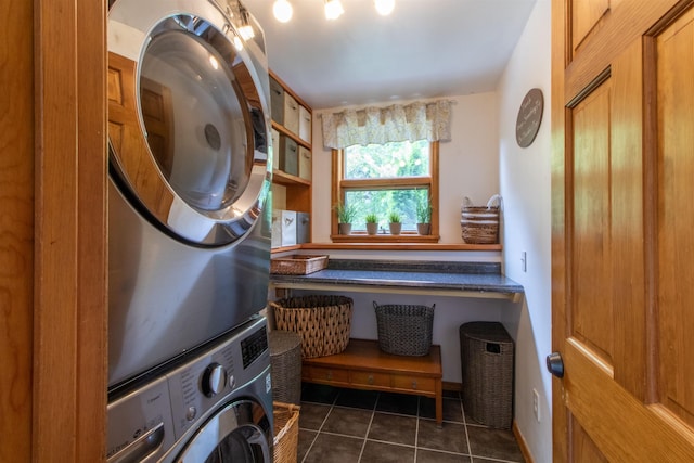 clothes washing area with dark tile patterned floors, laundry area, and stacked washing maching and dryer