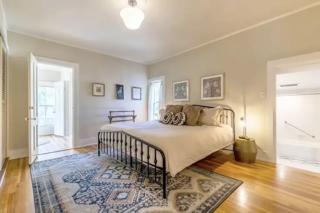 bedroom featuring multiple windows, wood finished floors, and connected bathroom