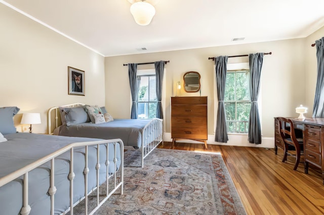bedroom with crown molding, visible vents, and wood finished floors