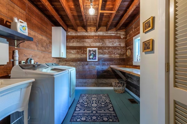 clothes washing area featuring wood walls, wooden ceiling, washing machine and clothes dryer, a sink, and cabinet space