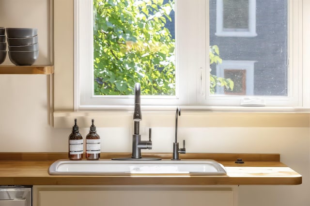 details with a sink, wood counters, and white cabinets
