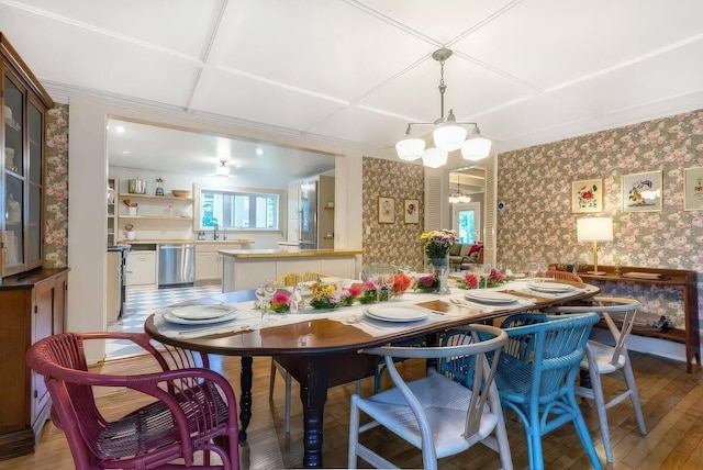 dining area with light wood finished floors, a notable chandelier, and wallpapered walls