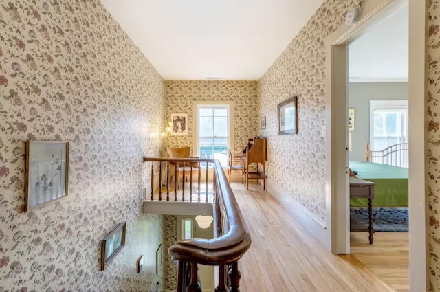 hallway with baseboards, wallpapered walls, and wood finished floors