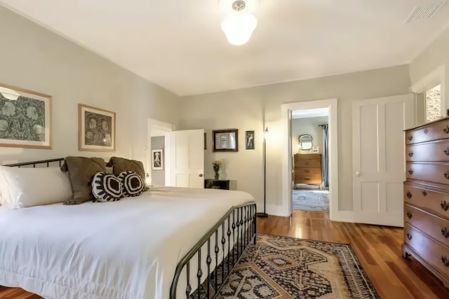 bedroom featuring baseboards, visible vents, and wood finished floors