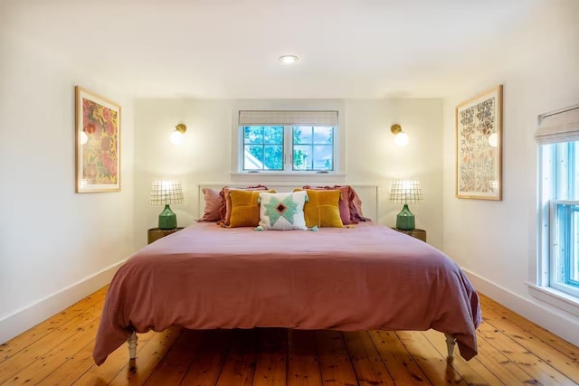 bedroom featuring baseboards, multiple windows, and light wood-style floors
