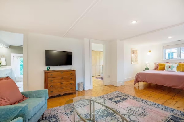 bedroom with recessed lighting, baseboards, ensuite bathroom, and light wood-style floors