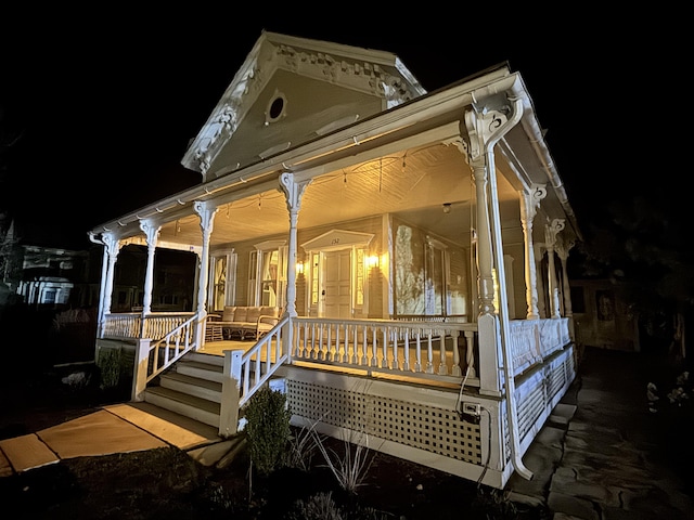 back of house at night featuring a porch