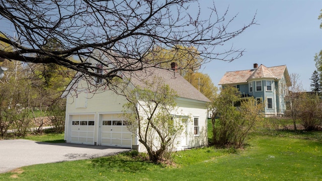 view of home's exterior with a lawn, a shingled roof, and driveway