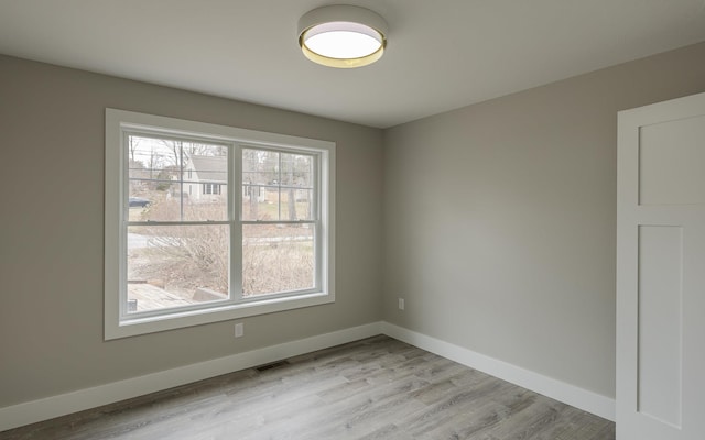 unfurnished room featuring baseboards, light wood-type flooring, and visible vents