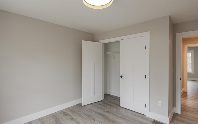 unfurnished bedroom featuring a closet, baseboards, and light wood-type flooring