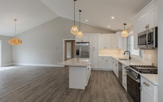 kitchen with a sink, vaulted ceiling, stainless steel appliances, and white cabinetry