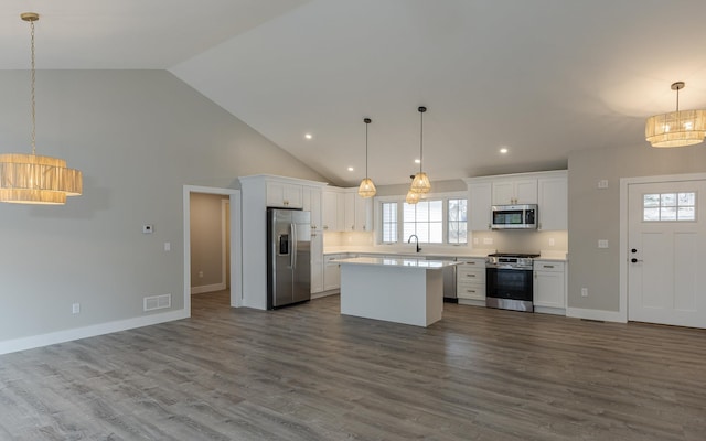kitchen featuring a kitchen island, appliances with stainless steel finishes, light countertops, open floor plan, and white cabinetry