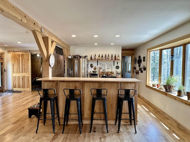 bar with indoor wet bar, recessed lighting, a barn door, and stainless steel fridge with ice dispenser