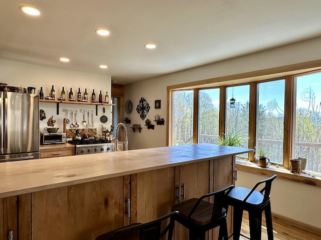 bar featuring a sink, stove, freestanding refrigerator, recessed lighting, and wood finished floors
