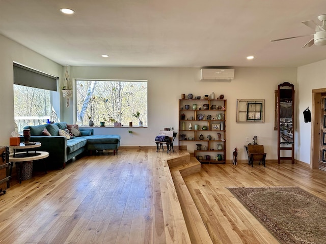 living area with a wall mounted AC, a ceiling fan, recessed lighting, and hardwood / wood-style floors