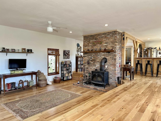 living area with recessed lighting, a ceiling fan, a wood stove, and hardwood / wood-style flooring