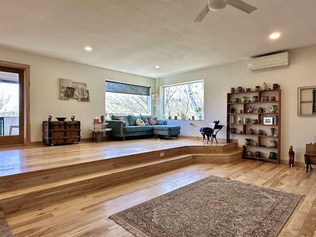 living area with recessed lighting, ceiling fan, a wall mounted AC, and hardwood / wood-style floors