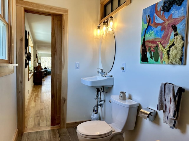 bathroom with toilet, baseboards, a sink, and wood finished floors
