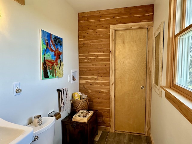 interior space with wooden walls, toilet, and wood finished floors