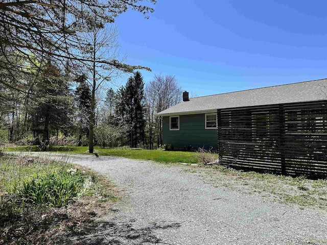 view of property exterior with a chimney and a shingled roof