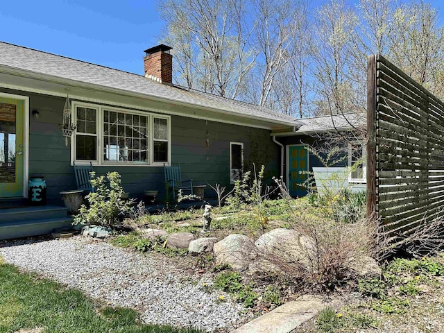 exterior space featuring a chimney and a shingled roof