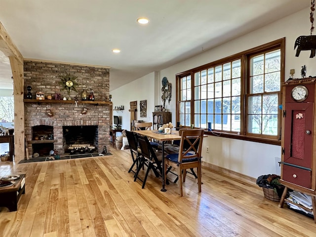 dining room featuring a fireplace, baseboards, wood-type flooring, and recessed lighting