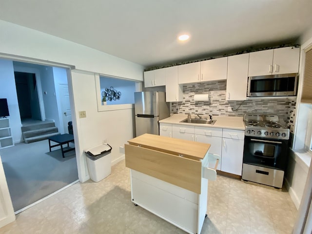 kitchen featuring backsplash, appliances with stainless steel finishes, a sink, light countertops, and white cabinets