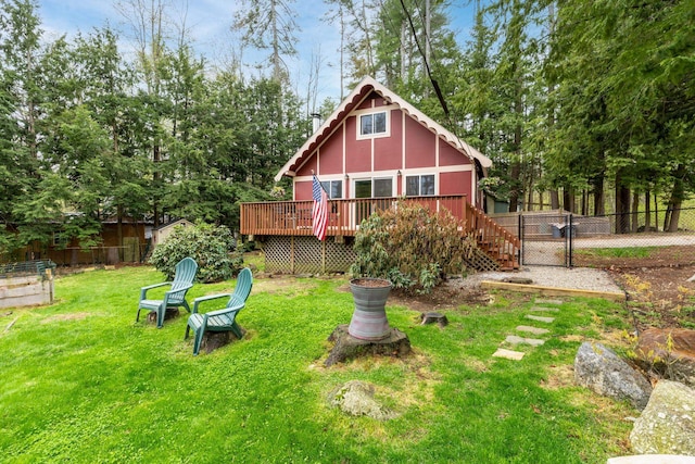 back of property featuring a lawn, a deck, fence, and a gate