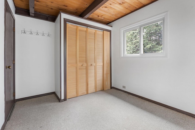 unfurnished bedroom featuring baseboards, light carpet, and wood ceiling