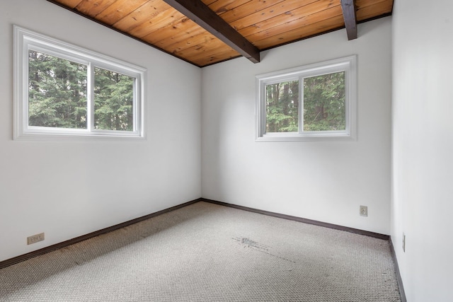 carpeted spare room featuring baseboards, beam ceiling, and wooden ceiling