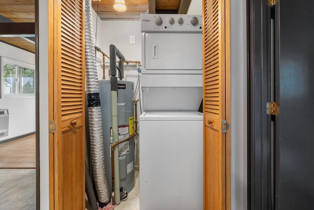 washroom featuring stacked washer and dryer, laundry area, and water heater