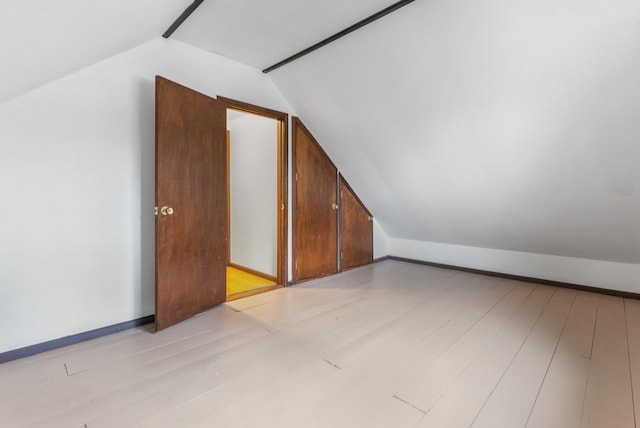 additional living space with vaulted ceiling and light wood-style flooring