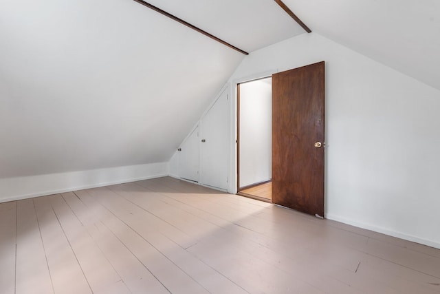 additional living space featuring light wood-style flooring and lofted ceiling