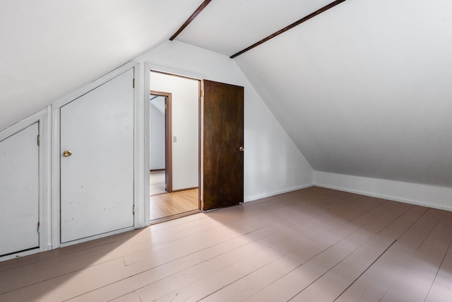 additional living space featuring light wood-style floors and lofted ceiling