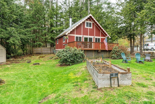 back of house featuring fence, a yard, a garden, and a deck