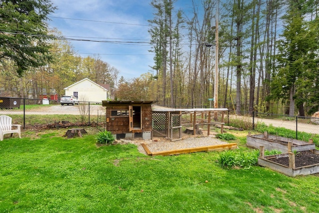 view of yard featuring fence, exterior structure, an outbuilding, and a vegetable garden