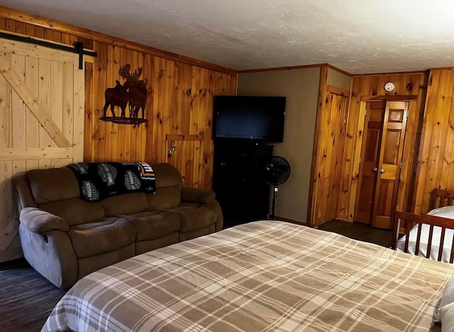 bedroom with wood walls, a barn door, and wood finished floors