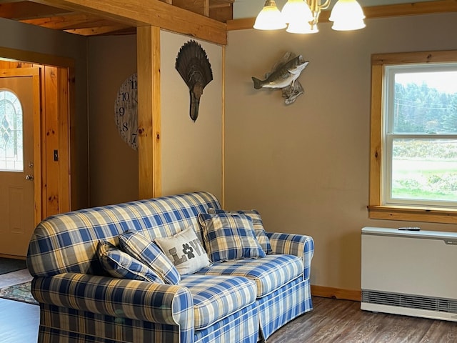 living room with a healthy amount of sunlight, heating unit, wood finished floors, and a notable chandelier