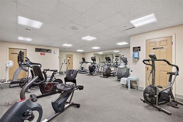 exercise room with baseboards and a paneled ceiling