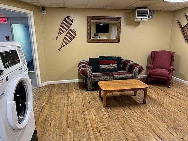living area with washer / dryer, light wood-style floors, and a paneled ceiling