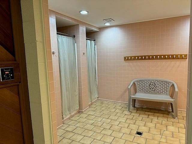 bathroom featuring tile walls, tile patterned flooring, a tile shower, and recessed lighting