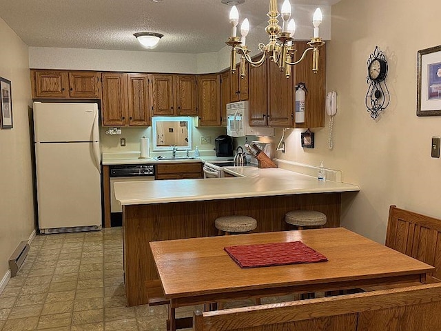 kitchen featuring a sink, light countertops, a peninsula, a notable chandelier, and white appliances