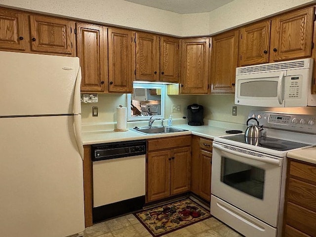 kitchen featuring a sink, brown cabinets, white appliances, and light countertops