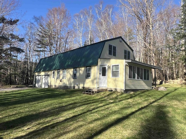 colonial inspired home featuring a garage, a gambrel roof, a front yard, and metal roof