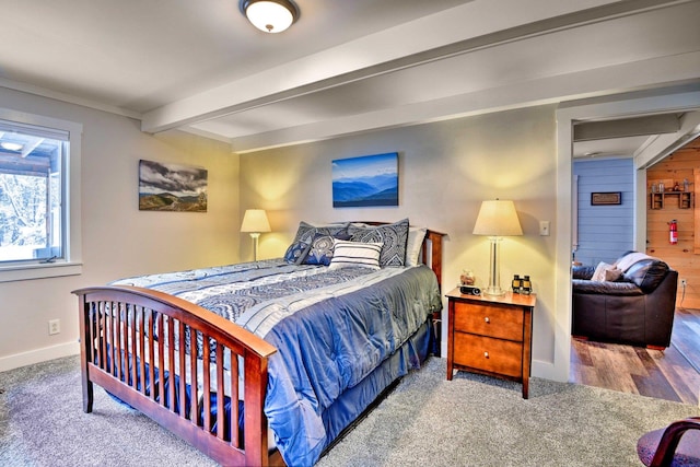 bedroom with baseboards, beam ceiling, and carpet
