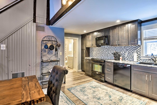 kitchen with light wood-type flooring, a sink, backsplash, and black appliances