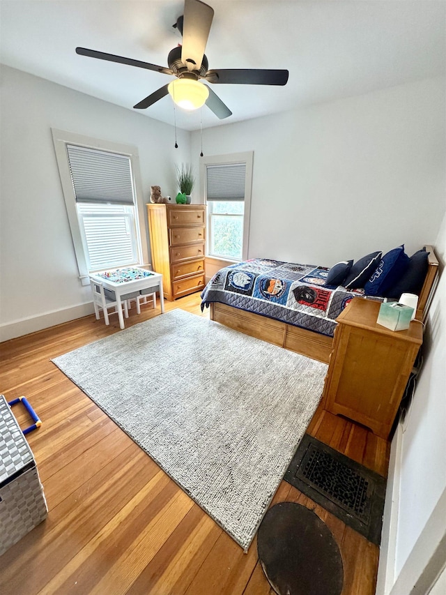 bedroom featuring baseboards, a ceiling fan, light wood finished floors, and visible vents