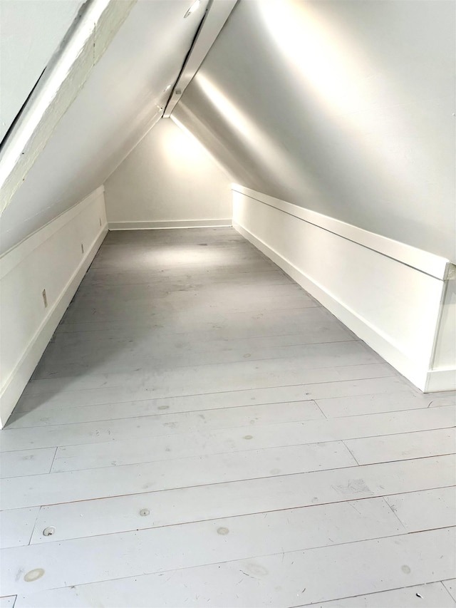 bonus room with baseboards, vaulted ceiling, and wood finished floors