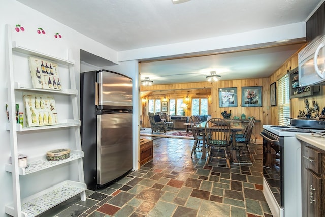 kitchen with light countertops, wooden walls, and white appliances
