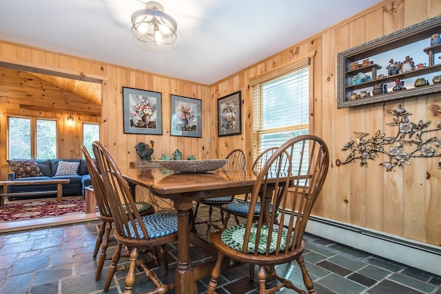 dining area featuring wooden walls, plenty of natural light, ornamental molding, and stone tile flooring